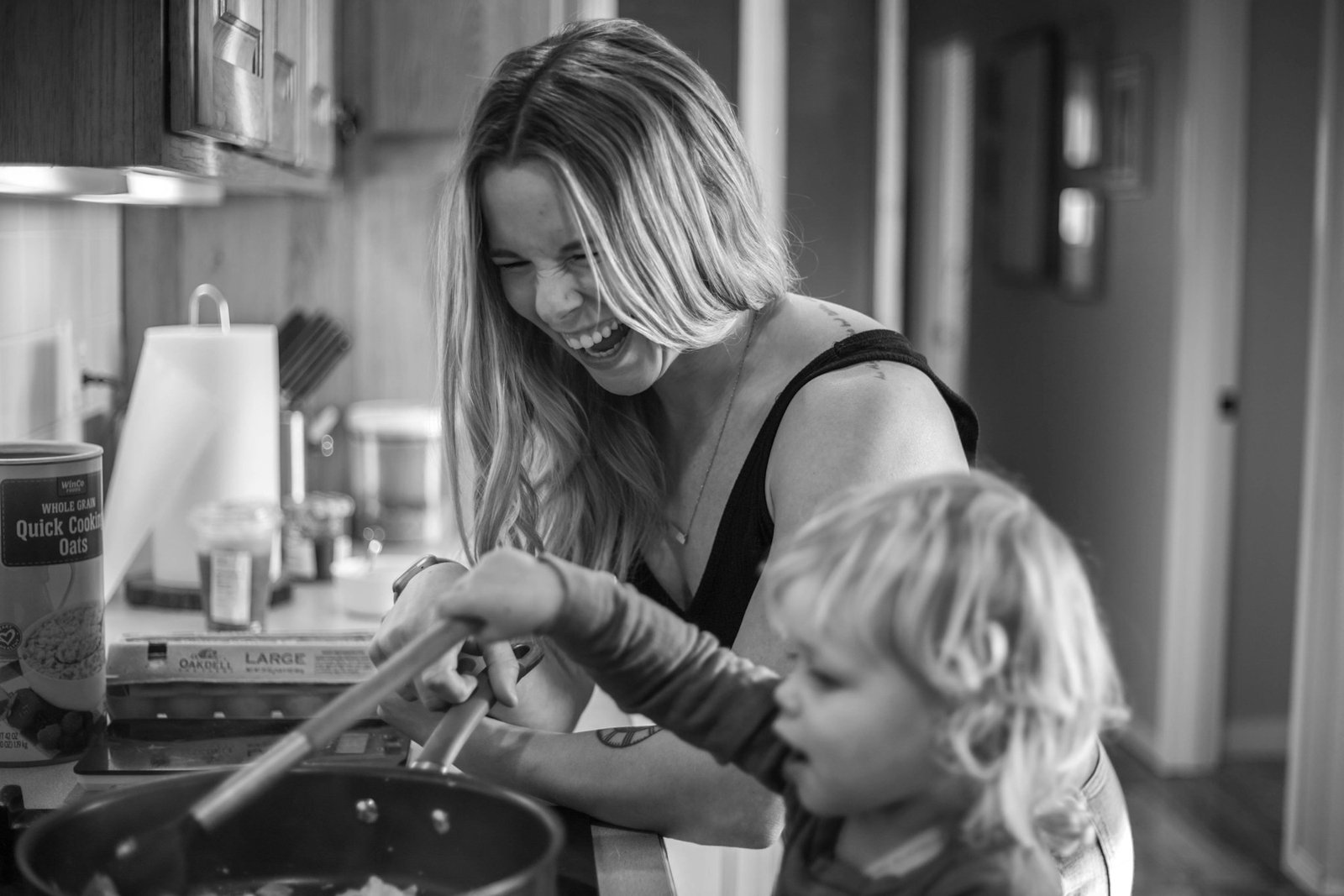 A mother and child laughing while cooking together