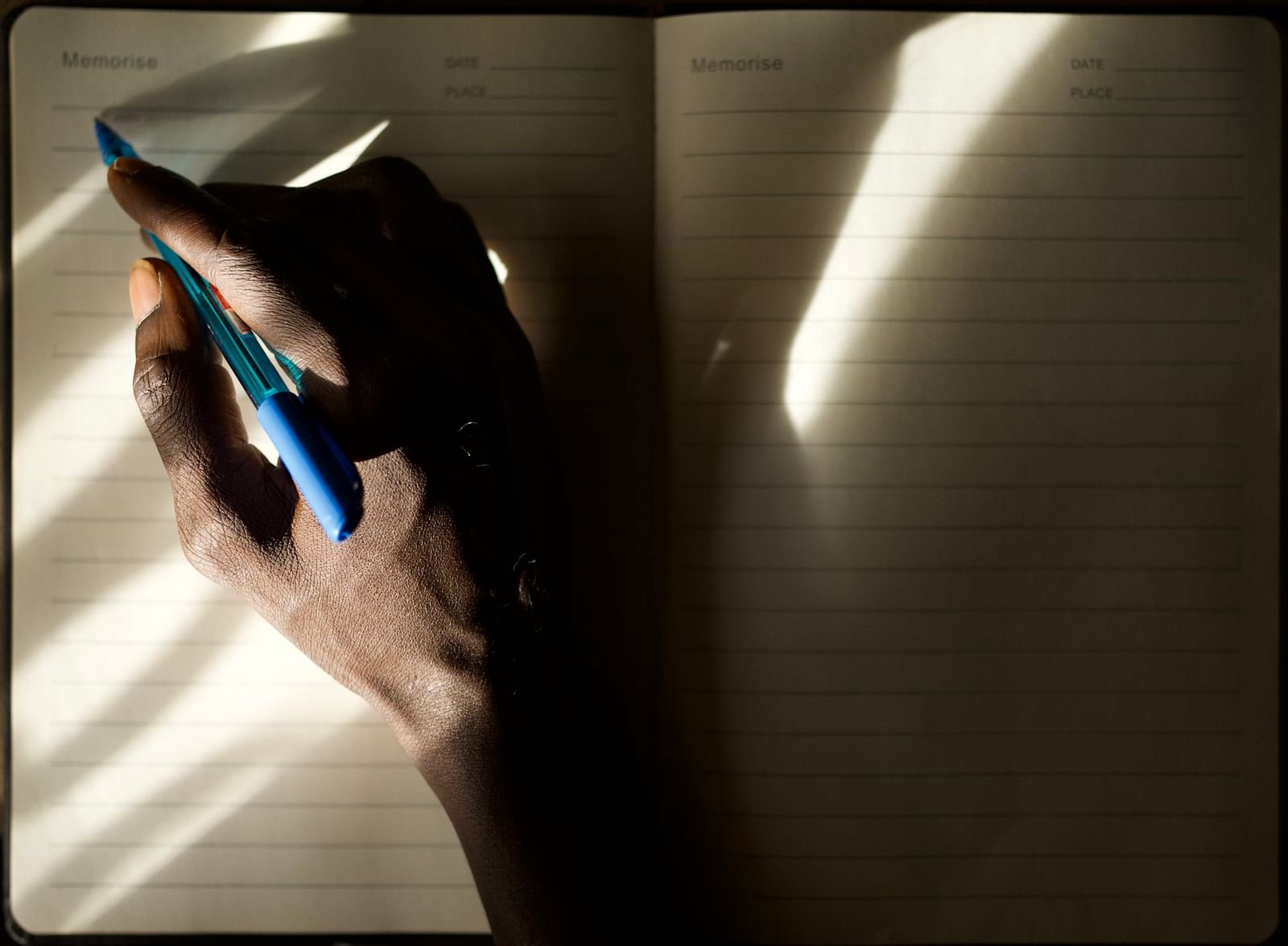 A hand writing in a journal in warm morning light